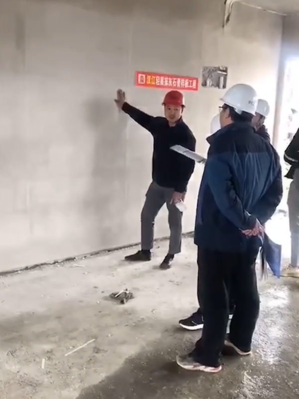 1627554386207657.jpg 公司總經理肖潤生(左一)在輕質抹灰石膏樣板工程向前來參觀的用戶介紹漢江牌輕質抹灰石膏的使用效果。.jpg
